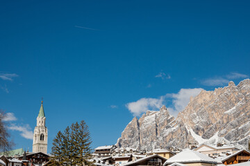 Sunny Winter View of Cortina d'Ampezzo with Snow Covered Rooftops and Dolomites Mountains, Italy