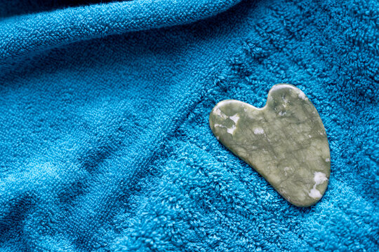 Guasha scraper made of natural serpentinite stone tool with soft towel, close-up