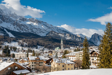 Sunny Winter View of Cortina d'Ampezzo with Snow Covered Rooftops and Dolomites Mountains, Italy