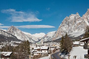 Sunny Winter View of Cortina d'Ampezzo with Snow Covered Rooftops and Dolomites Mountains, Italy