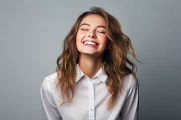 Obraz premium Young woman with closed eyes laughing cheerfully, portraying genuine happiness and good humor