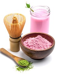 Still life with matcha, pink powder, whisk, and a glass of pink beverage on a white background