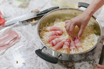 Enoki mushroom bacon cheese hand kitchen preparation cooking stainless steel pan homemade delicious Enoki mushroom wrapped bacon placed shredded cheese stainless steel pan hand arranging food