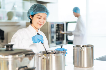 厨房で大鍋で調理する衛生白衣を着た女性調理師　給食センター　給食室 © metamorworks