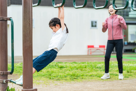 公園の雲梯で遊ぶ女の子