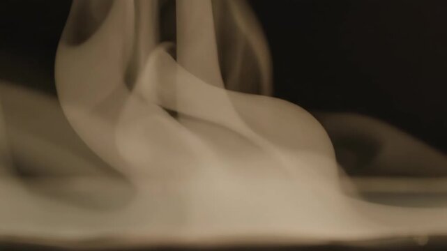 Smoke swirling in fluid motion, creating dynamic shapes and patterns against a dark background, showcasing the continuous flow and transformation of vapor