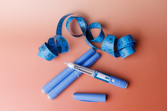 Injectable semaglutide pens for glucose control with a blue measuring tape on a clean background for weight loss and medical themes.