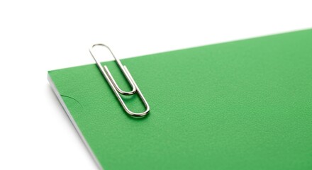 Silver paperclip on bright green document folder isolated minimal office stationery concept