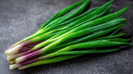 Fresh green onions with purple bases on a dark textured background