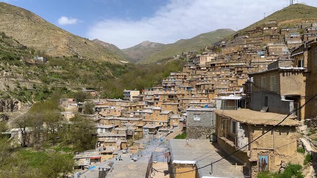 stepped brick village Kurdistan rugged slope Zagros mountain cascade stone traditional architecture local landscape cultural earthen roof rustic red Iran timber brown sunset golden hour green serene