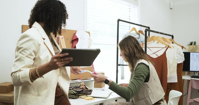 Diverse female designers collaborating over tablet sketch and swatches in studio finalizing style