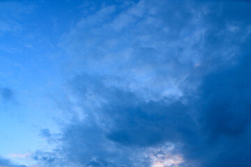 Fototapeta premium Expansive view of a deep blue evening sky filled with textured clouds, capturing the tranquil transition between day and night with soft natural gradients.