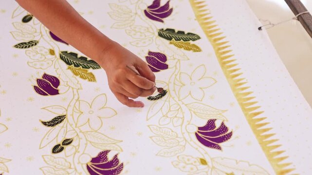 Indonesian artisan painting a traditional floral batik pattern