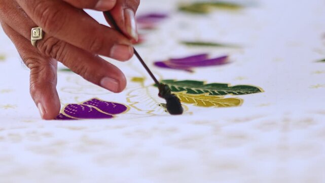 Indonesian artist painting traditional floral batik fabric