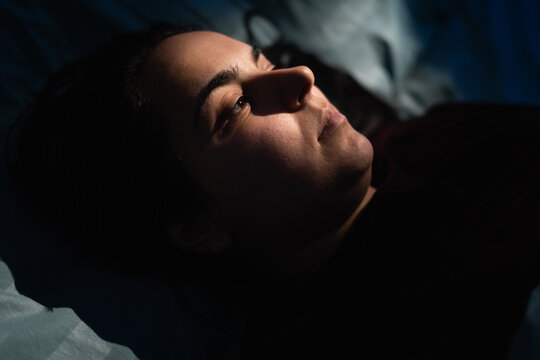Close-up of woman face in night light. Girl drifts off sleep in her bed. insomnia, sleep disorder, poor rest and sleepless nights