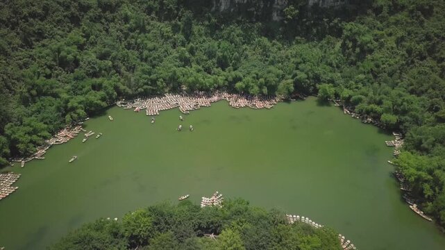 High angle view of tour boats moored on the green riverbank surrounded by a lush tropical forest