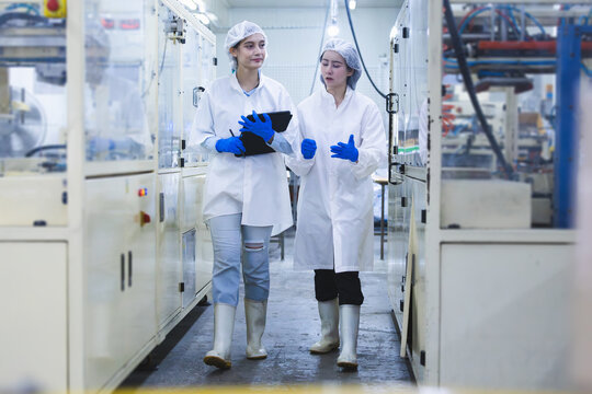 Factory staff using digital tablet for data recording and operational check in a manufacturing plant, Quality control officers walking through production line and collaborating on factory management