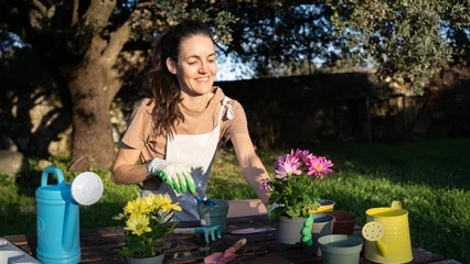 Plexiglas schilderij Zorgcentrum Woman enjoying gardening hobby repotting flowers outdoors in sunlight  © Arianne