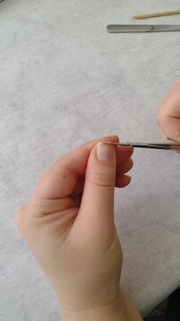 First person POV of cutting a thumbnail with small manicure scissors. Close up shot of personal nail care routine at home, precise grooming process, everyday hygiene and beauty maintenance footage.