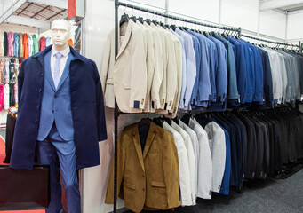 Obraz premium Mannequin wearing a suit and suits neatly arranged on hangers in a clothing store interior. Men's business attire. Sale concept.