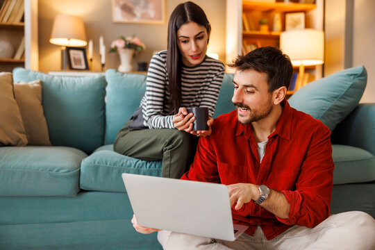 Couple searching for vacation online booking ideas using laptop computer while relaxing at home