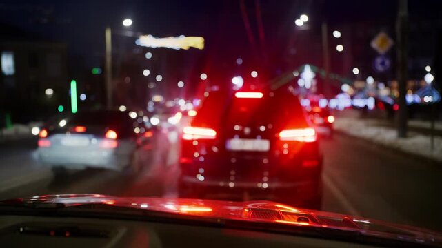 Night city traffic with multiple vehicles ahead, brake lights glowing red and streetlights lining the road