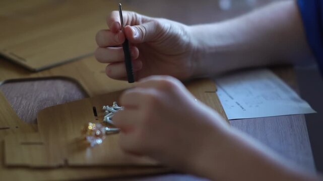 teenager assembling a shelf. A teenager assembles a bookshelf. A child tries on parts to assemble furniture.