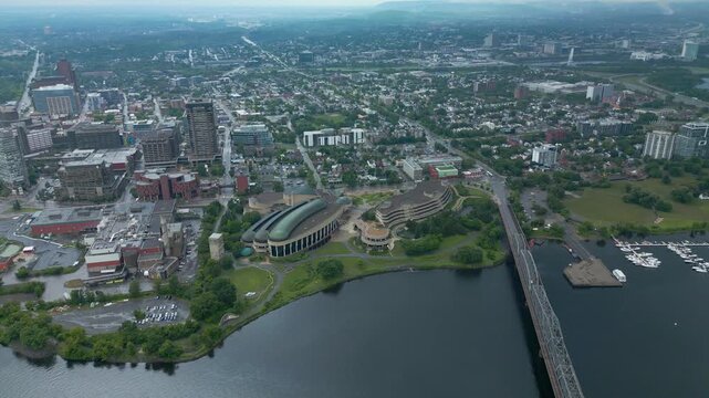 overhead summer perspective drone view of the Canadian History Museum's Indigenous Experiences buildings situated along the waterfront of the Ottawa river calm water next to the Alexandra bridge brg