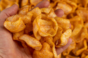 crispy mashed potato chips fried in a large amount of sunflower oil, sprinkled with red pepper spices, crispy delicious high-calorie chips with spices are scattered on the table