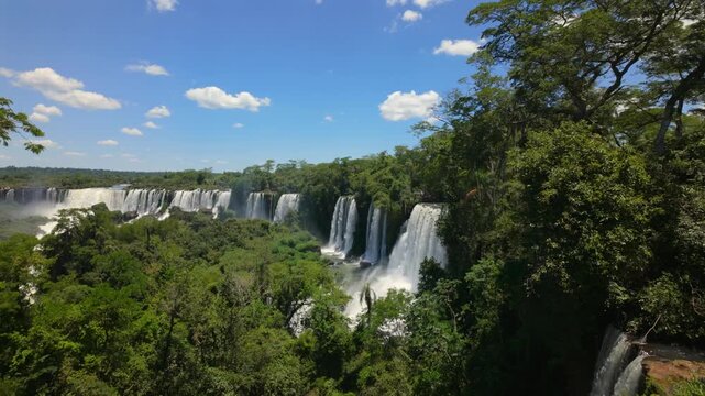 Dolly in toward Alvar Nunez waterfalls across green rainforest gorge, Iguazu Falls Argentina.
