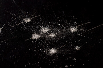 dents and dots on the glass where it broke, white cracks and completely broken glass on a black uneven background