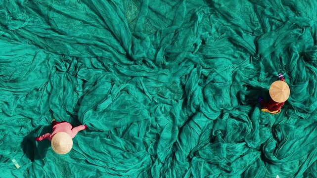 Vietnamese fisherman workers sorting green fishing nets outdoors, Aerial view Viet travel video.