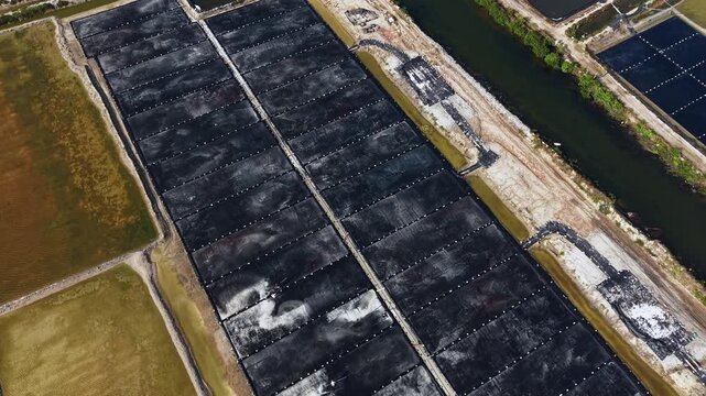 Aerial top view of people working on traditional salt mining fields industry in Vietnam.