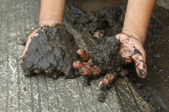A child's hands are happily playing with mud outdoors. The concept of free play, sensory exploration, and childhood development.