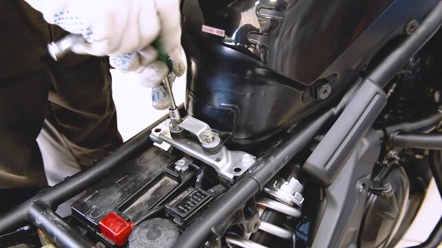 The process of replacing or servicing the air filter on a motorcycle. A mechanic removes plastic from a motorcycle. Removing plastic parts from a motorcycle.