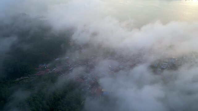 Aerial perspective captures Pulau Pangkor, morning mist veiling coastal villages and shimmering sea.