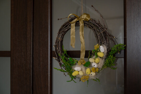 Handmade Easter wreath festive yellow egg decorations on front door. Traditional holiday preparation craft creative decor. Sustainable responsible holiday gift workshop creation. Copy space Simple