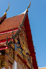 Obraz premium Ornate roof and golden statue decorations at Wat Mongkhon Nimit Buddhist Temple, Phuket Old Town, Thailand
