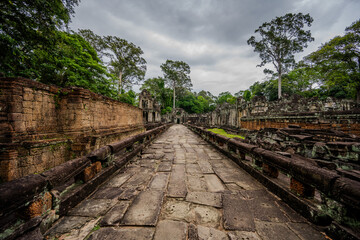 Naklejka premium Ancient stone walkway through Ta Prohm temple ruins in Cambodia
