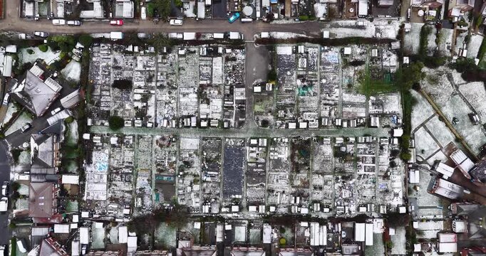 Straight down aerial drone footage of the village of Starbeck in Harrogate in North Yorkshire in the winter time showing a birds eye view of light snow covered houses and garden allotments