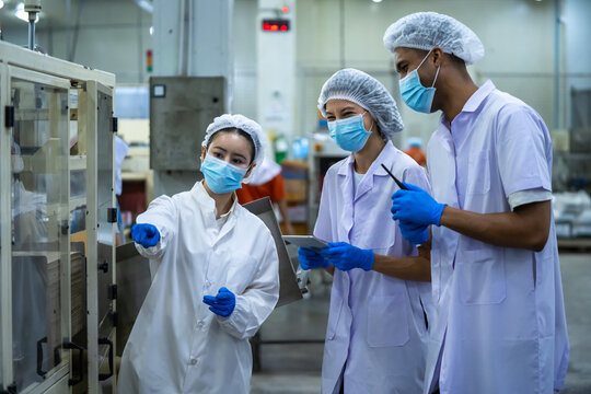 Production team meeting at automated packaging line in food manufacturing plant