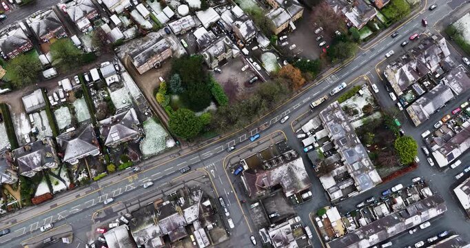 Straight down aerial drone footage of the town of Harrogate in North Yorkshire in the winter time showing the roof tops of snow covered houses and homes along side the streets and T-junction