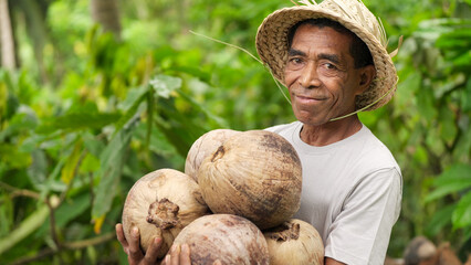 coconut farming, portrait of indonesian farmer on farm smiling, looking at camera, in straw hat, on flores island, indonesia, southeast asia, copra farming © Spice Footage