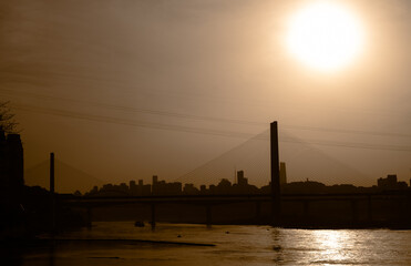 Fototapeta premium The silhouettes of city skyline surrounded by the sea under the sunlight during the sunset in Chongqing, China