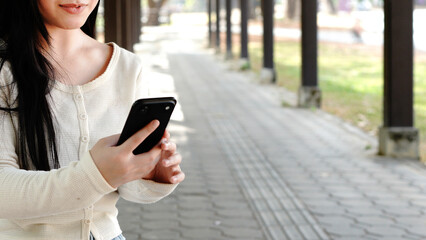 Close up woman hand hold using smart phone on outdoor park street background