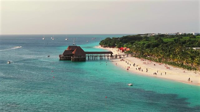 Panning view of traditional wooden bungalow with thatched roof and pier bridge on stilts.Kendwa beach with sand and ocean. Nungwi and Kendwa beach coastline, Zanzibar, Tanzania.