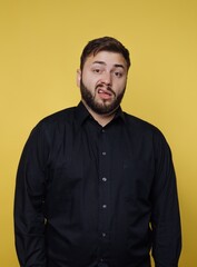 Fototapeta premium Man striking a playful pose with a cheeky expression against a bright yellow background in a casual indoor setting