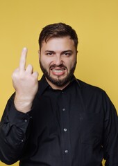 Fototapeta premium Strong emotions expressed by a man in a black shirt against a vibrant yellow background
