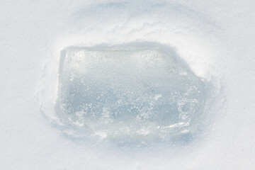 Ice block in the light blue tones on a white fluffy snow background.	

