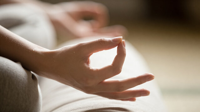 Woman holding her hands in gyan mudra while meditating, finding calm and balance, focusing on mindfulness, spirituality, and inner peace during a yoga session at home